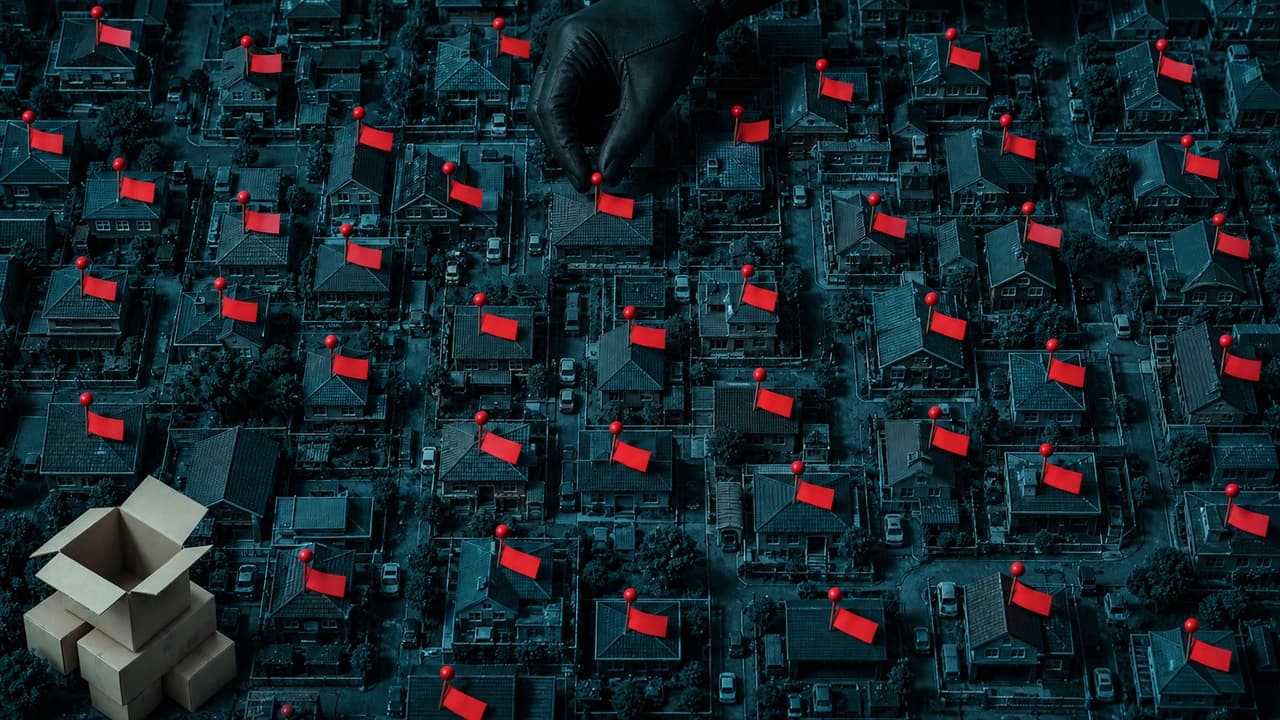 Top-down view of a dense residential district model in cold teal, rooftops packed edge to edge, dozens of red map pins with small blank tags standing out of scattered houses, a cropped gloved hand pressing another pin into one roof, and opened delivery cartons stacked at one corner.